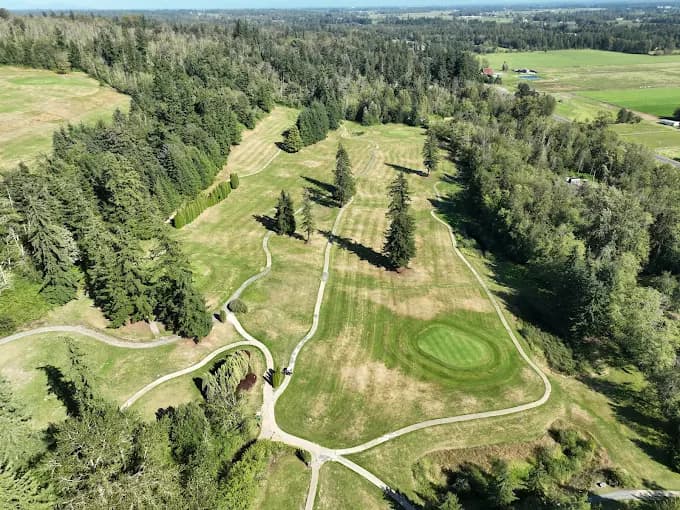 Aerial view of Dakota Creek Golf Course fairways winding through evergreen trees